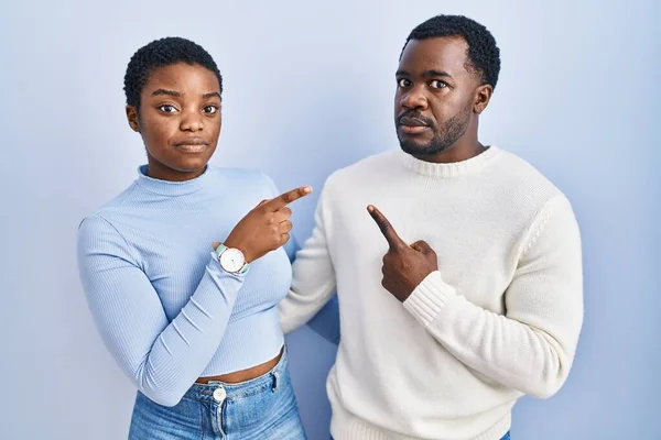 Jong Afrikaans Amerikaans Paar Staande Blauwe Achtergrond Wijzend Met Hand — Stockfoto