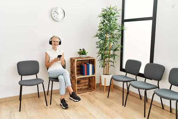 Mujer Rubia Joven Usando Teléfono Inteligente Auriculares Sentados Silla Sala — Foto de Stock