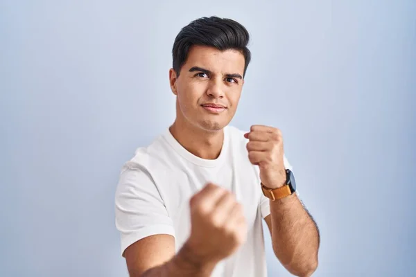 Hispanic Man Standing Blue Background Ready Fight Fist Defense Gesture — Stockfoto