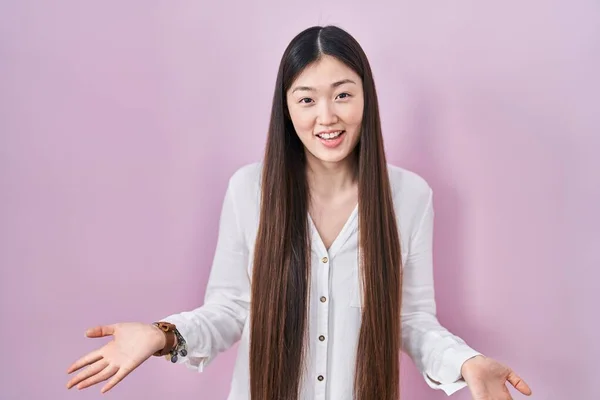 中国年轻女子站在粉红的背景上 张开双臂 愉快地微笑着 友好地欢迎 积极地 自信地问候着 — 图库照片
