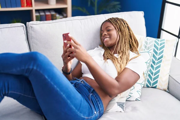 Afroamerykanka Pomocą Smartfona Leżącego Kanapie Domu — Zdjęcie stockowe
