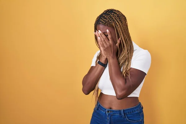 泣きながら手で顔を覆う悲しい表情で黄色の背景に立って編組髪を持つアフリカ系アメリカ人女性 うつ病の概念 — ストック写真