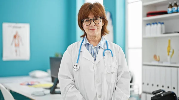 中年妇女医生微笑着自信地站在诊所 — 图库照片