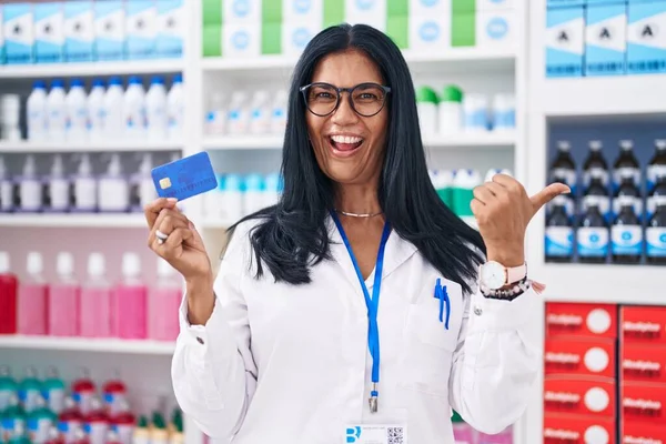 Mature Hispanic Woman Working Pharmacy Drugstore Holding Credit Card Pointing — Stock Photo, Image