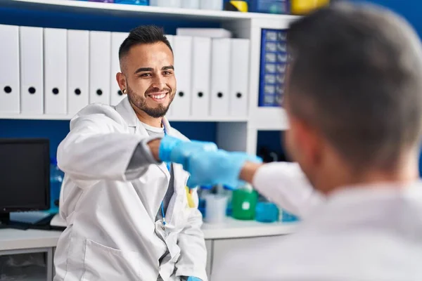 Dwóch Naukowców Uśmiechających Się Pewnie Uderzając Pięściami Laboratorium — Zdjęcie stockowe