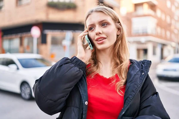 Genç sarışın kadın gülümsüyor. Kendine güveni tam. Akıllı telefondan konuşuyor.