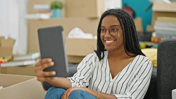 アフリカ系アメリカ人の女性がビデオ通話を持っている新しい家の床に座って — ストック写真