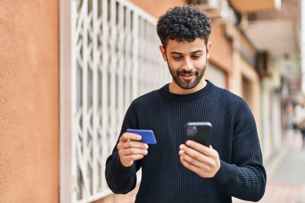 stock image Young arab man using smartphone and credit card at street