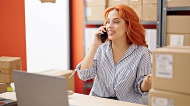 Genç kızıl saçlı kadın, iş kadını. Ofiste bilgisayarla konuşuyor.