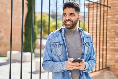 Sokakta akıllı telefon kullanan, kendine güvenen genç bir İspanyol.