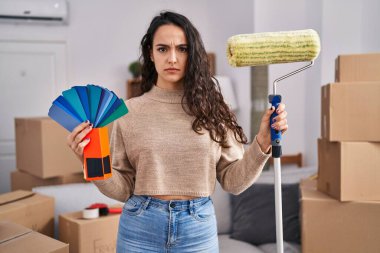 Genç esmer kadın yeni bir eve taşınıyor duvarları kuşkucu ve gergin boyuyor, sorun yüzünden surat asıyor. negatif kişi. 