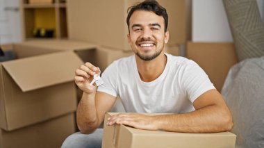 Yeni evin anahtarlarını elinde tutarak gülümseyen İspanyol genç adam.