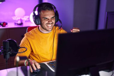 Oyun odasında bilgisayar kullanarak video oyunu oynayan İspanyol asıllı genç adam.