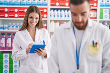 Eczanede çalışan erkek ve kadın eczacılar dokunmatik ped kullanıyorlar.