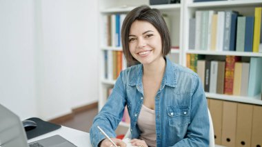 Genç beyaz kız öğrenci üniversite sınıfında dizüstü bilgisayar kullanıyor.