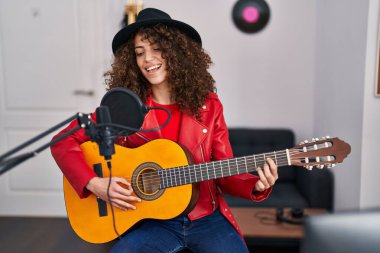 Genç İspanyol kadın müzisyen müzik stüdyosunda klasik gitar çalıyor.