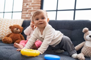 Evdeki kanepede oturan sevimli beyaz çocuk basketbol oynuyor.