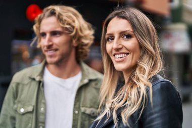 Erkek ve kadın bir arada durarak gülümsüyor.