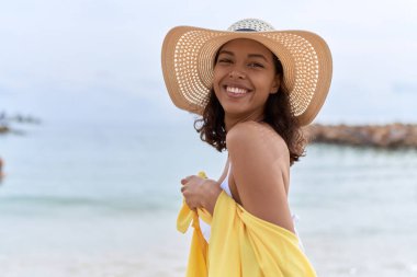 Young african american woman smiling confident wearing summer hat and bikini at beach