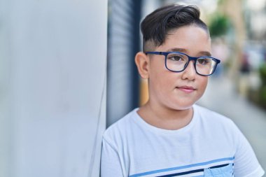 Adorable hispanic boy smiling confident looking to the side at street