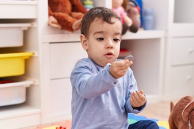 Anaokulunda rahat bir ifadeyle yerde oturan sevimli İspanyol çocuk.