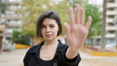 Young caucasian woman doing stop gesture with hand at park