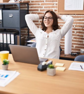 Young woman business worker relaxed with hands on head using laptop at office
