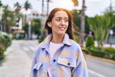 Young beautiful hispanic woman smiling confident looking to the side at street