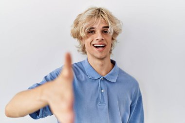 Soyutlanmış arka planda duran genç ve modern bir adam dostça bir selamlama ve hoş geldin hediyesi olarak tokalaşıyor. başarılı iş. 