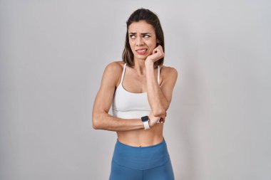 Tecrit edilmiş arka planda spor kıyafeti giyen İspanyol kadın bir soru hakkında endişeli ve gergin bir şekilde düşünüyor. 