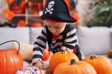 Korsan kostümü giyen sevimli beyaz çocuk elinde şeker tutuyor.