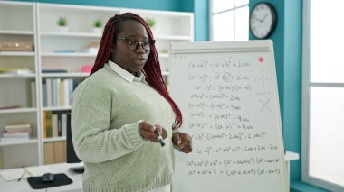 Örgü örmüş saç öğretmeni olan Afrikalı kadın üniversite kütüphanesinde matematik dersi veriyor.