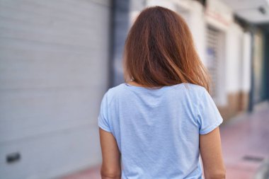 Young woman standing on back view at street