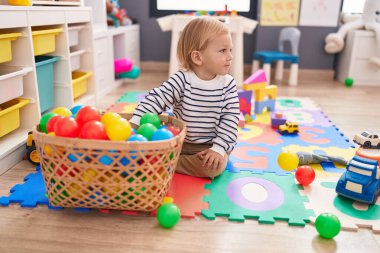 Anaokulunda yerde taşaklarıyla oynayan sevimli beyaz çocuk.