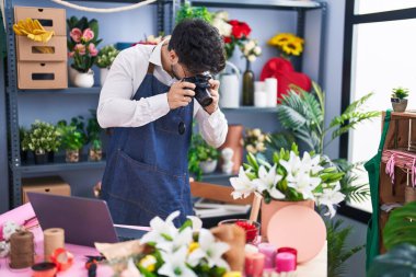 Young hispanic man florist make photo to flowers at florist shop