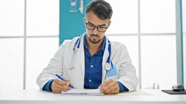 Genç İspanyol doktor klinikte tıbbi rapor yazıyor.