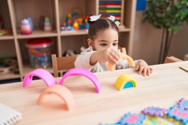 Anaokulundaki masada oturan, inşaat bloklarıyla oynayan sevimli İspanyol kız.