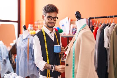 Genç İspanyol terzi atölyede manikinin yanında kahve içiyor.