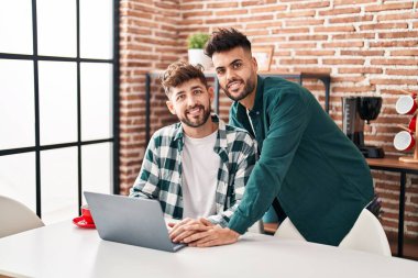 Young couple using laptop sitting on table at home
