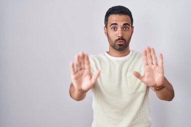 Soyutlanmış arka planda duran İspanyol sakallı bir adam. Avuçlarını hareket ettiriyor. Korkmuş ve iğrenç bir ifadeyle reddediyor. Dur ve yasakla. 