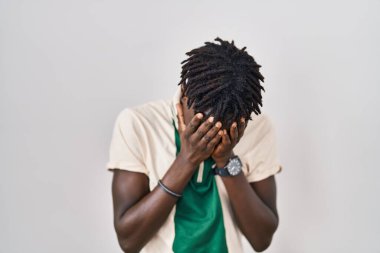 Afrikalı bir adam izole edilmiş arka planda duruyor. Ağlarken suratını ellerle kapatıyor. depresyon kavramı. 