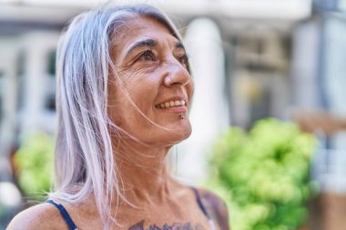 Middle age grey-haired woman smiling confident looking to the side at street