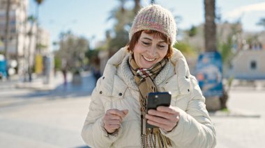 Sokakta akıllı telefon kullanan, kendine güvenen, olgun İspanyol kadın.