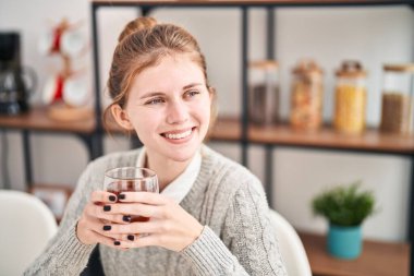 Yemek odasındaki masada çay içen genç sarışın kadın.