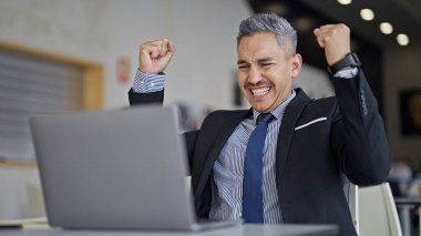 Genç İspanyol iş adamı laptopunu kullanarak ofiste birinci sınıf bir jest yapıyor.