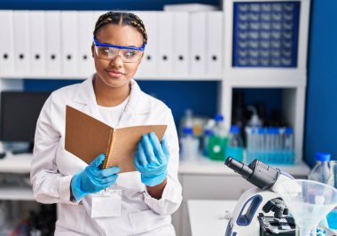 Laboratuvarda kitap okuyan Afrikalı Amerikalı kadın bilim adamı.