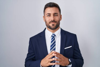 Yakışıklı, takım elbiseli, ellerini birbirine bağlayan ve gülümseyen, gevşemiş ve neşeli bir İspanyol. Başarı ve iyimserlik 