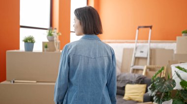 Genç beyaz kadın yeni evinde geriye doğru duruyor.