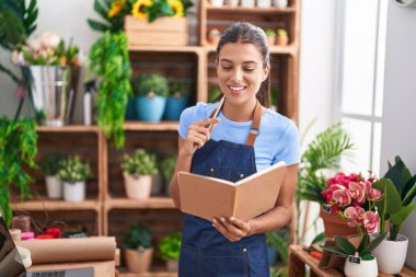 Çiçekçiye gülümseyen güzel İspanyol kadın çiçekçiye not defteri okuyor.