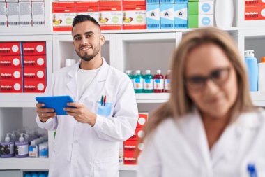 Man and woman pharmacist using touchpad working at pharmacy